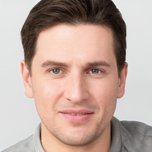 Joyful white young-adult male with short  brown hair and grey eyes