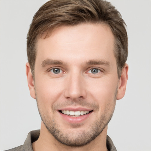 Joyful white young-adult male with short  brown hair and grey eyes