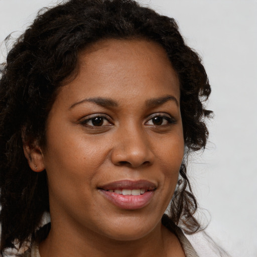 Joyful black young-adult female with long  brown hair and brown eyes