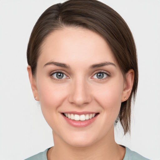 Joyful white young-adult female with medium  brown hair and grey eyes