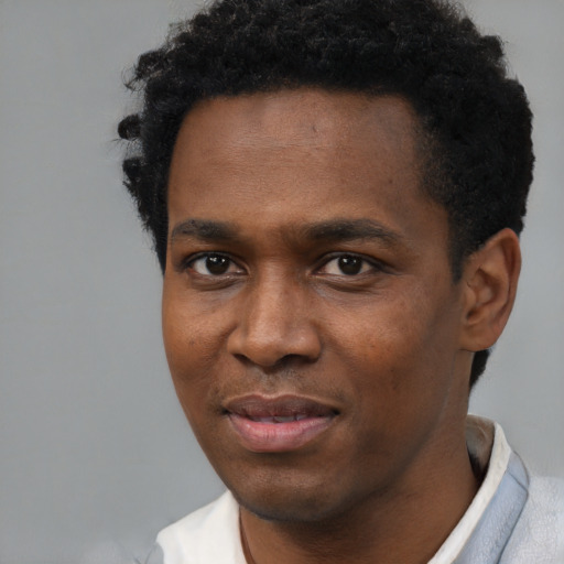 Joyful black young-adult male with short  black hair and brown eyes