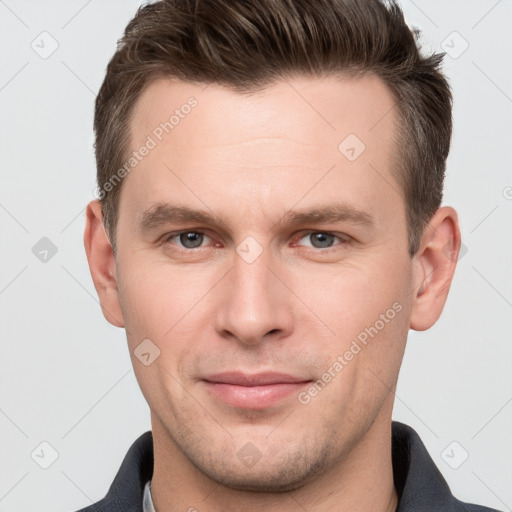 Joyful white young-adult male with short  brown hair and grey eyes