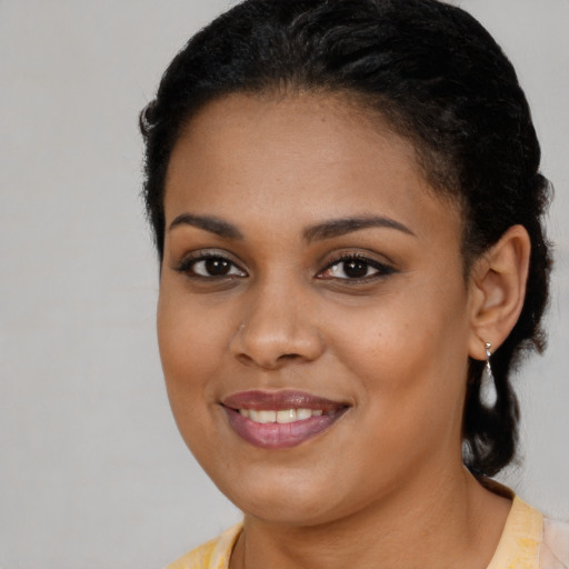 Joyful black young-adult female with long  brown hair and brown eyes