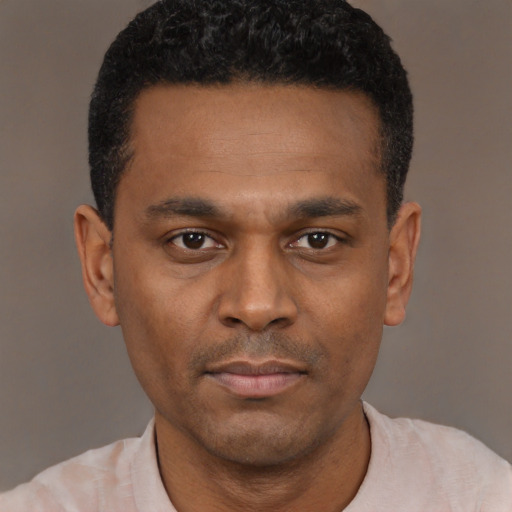 Joyful black young-adult male with short  black hair and brown eyes