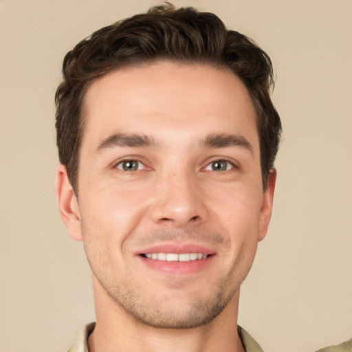 Joyful white young-adult male with short  brown hair and grey eyes