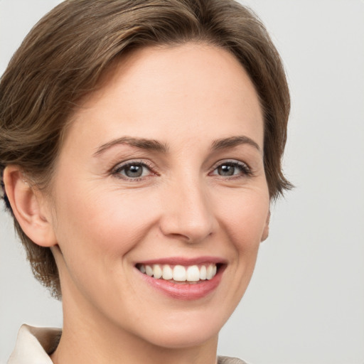 Joyful white young-adult female with medium  brown hair and grey eyes