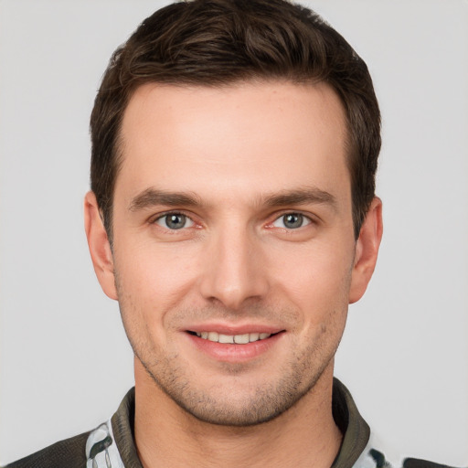 Joyful white young-adult male with short  brown hair and grey eyes