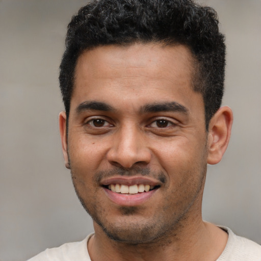 Joyful latino young-adult male with short  black hair and brown eyes