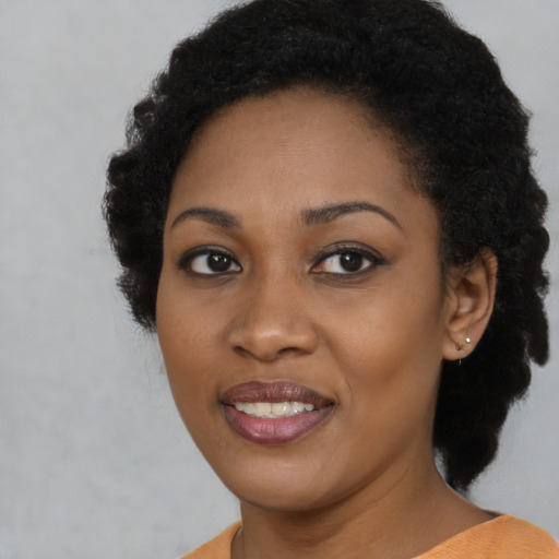 Joyful black young-adult female with short  black hair and brown eyes