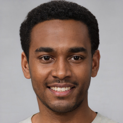 Joyful black young-adult male with short  black hair and brown eyes