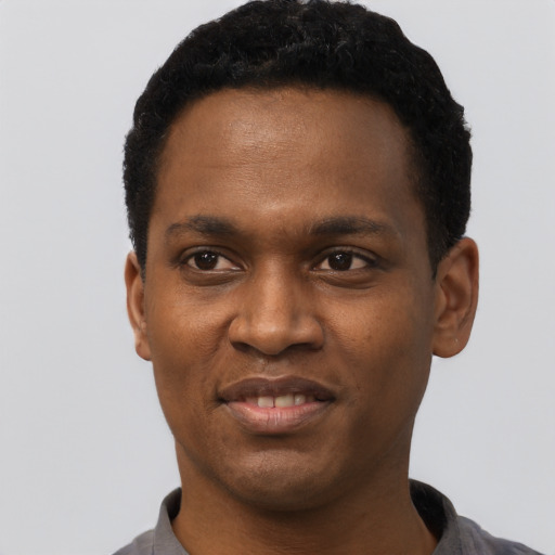 Joyful black young-adult male with short  black hair and brown eyes