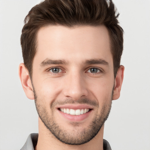 Joyful white young-adult male with short  brown hair and grey eyes