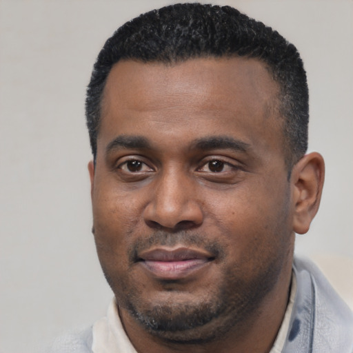 Joyful black young-adult male with short  black hair and brown eyes