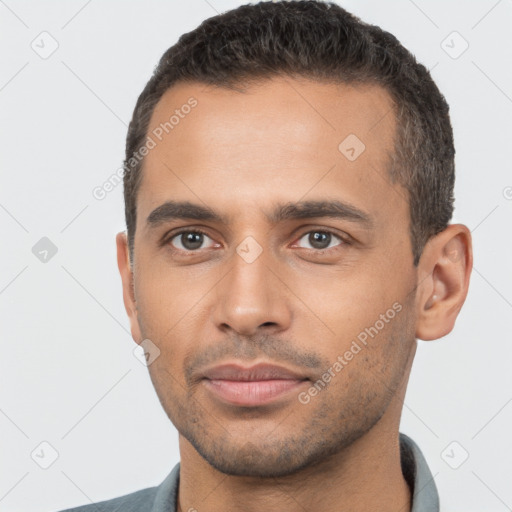 Joyful latino young-adult male with short  black hair and brown eyes