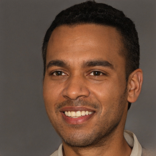 Joyful black young-adult male with short  brown hair and brown eyes