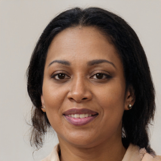 Joyful black adult female with medium  brown hair and brown eyes