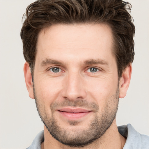 Joyful white young-adult male with short  brown hair and grey eyes