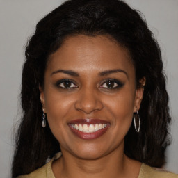 Joyful black young-adult female with long  brown hair and brown eyes