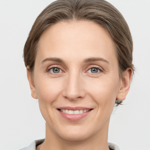 Joyful white young-adult female with medium  brown hair and grey eyes