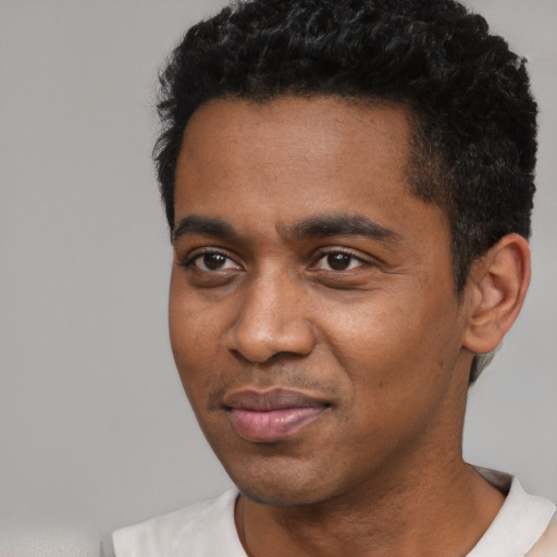 Joyful black young-adult male with short  black hair and brown eyes