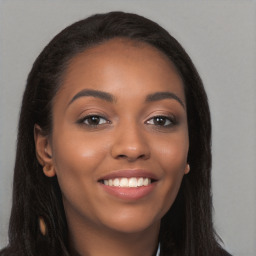 Joyful black young-adult female with long  brown hair and brown eyes