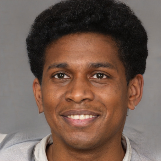 Joyful black young-adult male with short  black hair and brown eyes