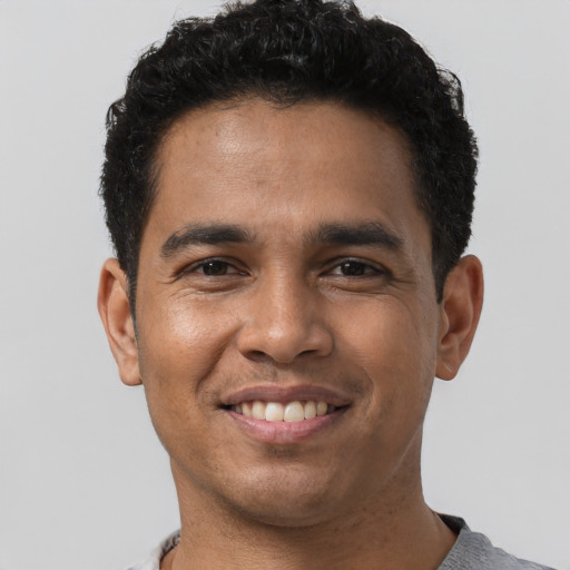Joyful latino young-adult male with short  brown hair and brown eyes