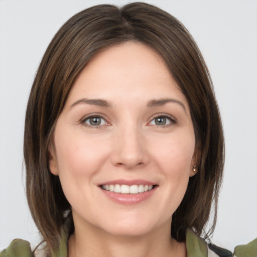 Joyful white young-adult female with medium  brown hair and grey eyes