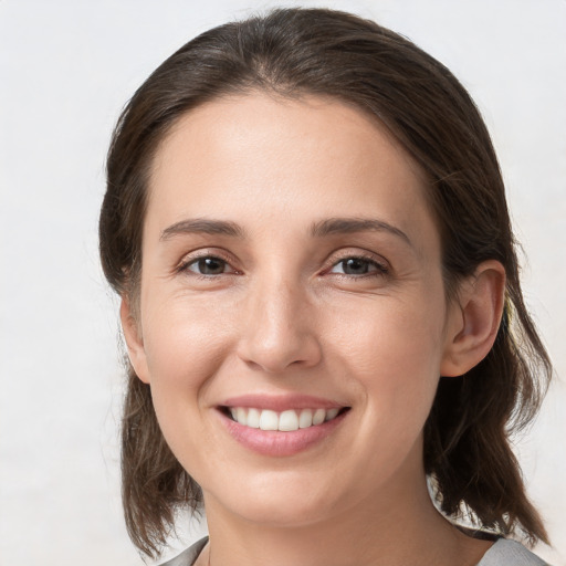 Joyful white young-adult female with medium  brown hair and grey eyes