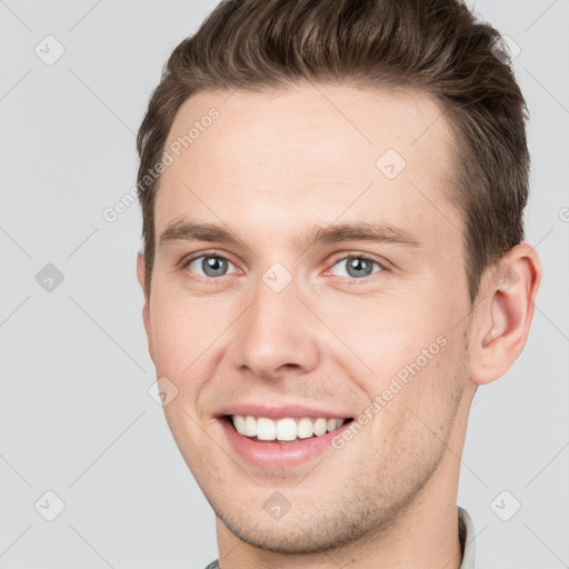 Joyful white young-adult male with short  brown hair and grey eyes