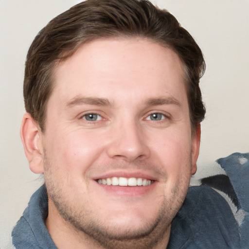 Joyful white young-adult male with short  brown hair and blue eyes