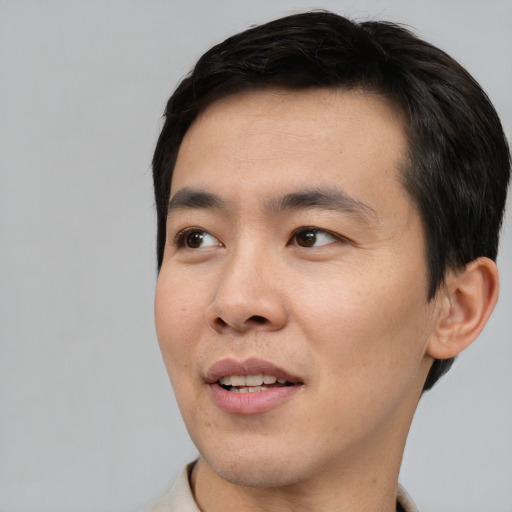 Joyful asian young-adult male with short  black hair and brown eyes