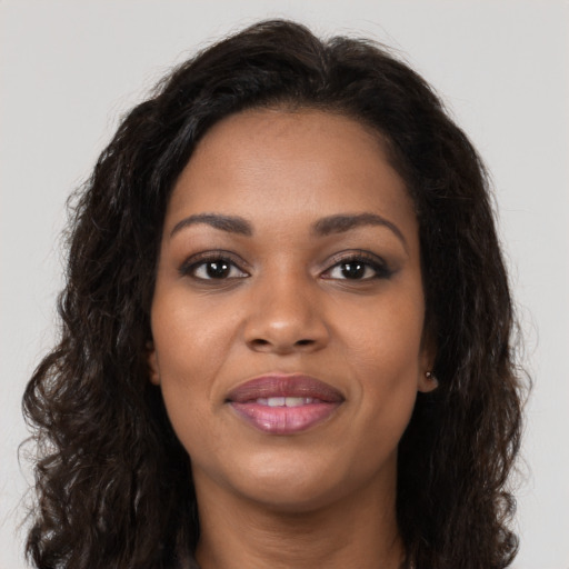 Joyful black young-adult female with long  brown hair and brown eyes