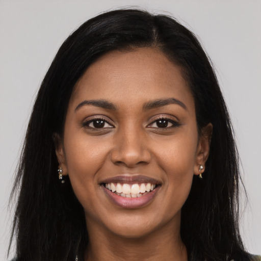 Joyful black young-adult female with long  brown hair and brown eyes