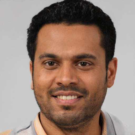 Joyful latino young-adult male with short  black hair and brown eyes