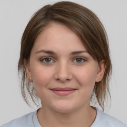 Joyful white young-adult female with medium  brown hair and grey eyes