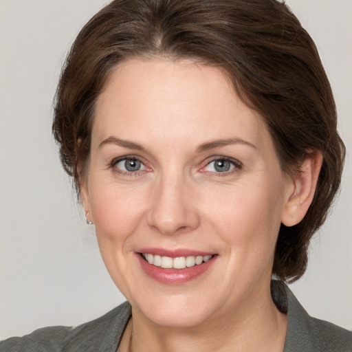 Joyful white adult female with medium  brown hair and grey eyes