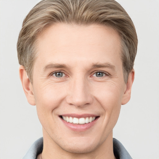 Joyful white young-adult male with short  brown hair and grey eyes