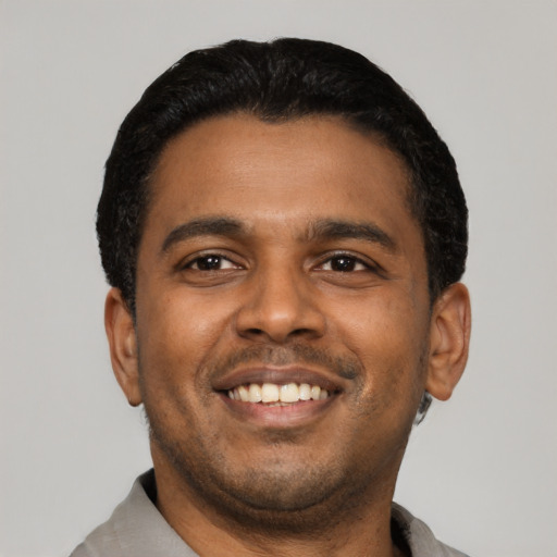 Joyful latino young-adult male with short  black hair and brown eyes