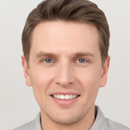 Joyful white young-adult male with short  brown hair and grey eyes