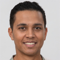 Joyful latino young-adult male with short  brown hair and brown eyes