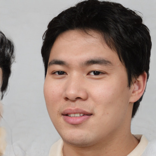 Joyful asian young-adult male with medium  black hair and brown eyes