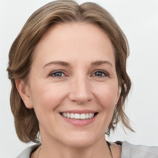 Joyful white young-adult female with medium  brown hair and grey eyes