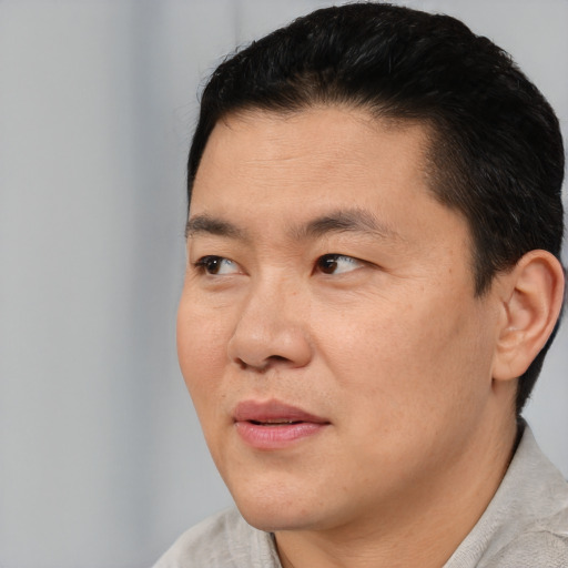 Joyful asian adult male with short  black hair and brown eyes