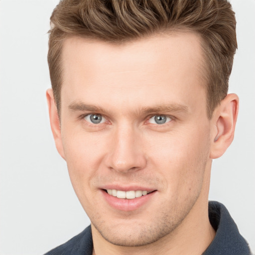 Joyful white young-adult male with short  brown hair and grey eyes