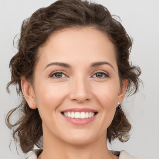 Joyful white young-adult female with medium  brown hair and grey eyes