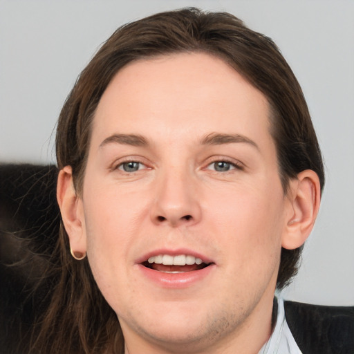 Joyful white young-adult male with long  brown hair and brown eyes