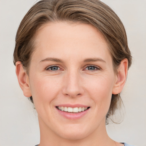 Joyful white young-adult female with medium  brown hair and grey eyes