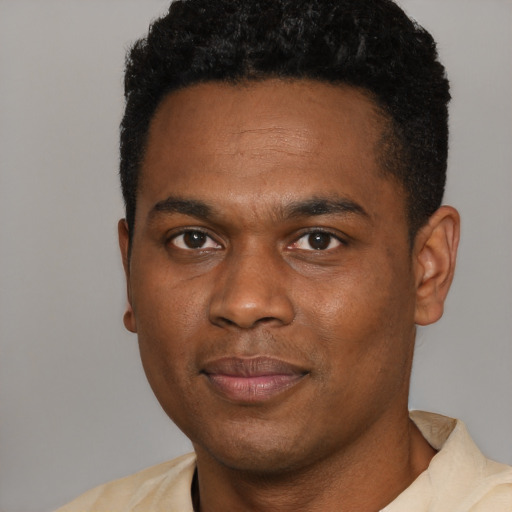 Joyful black young-adult male with short  black hair and brown eyes