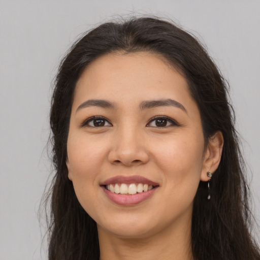 Joyful latino young-adult female with long  brown hair and brown eyes